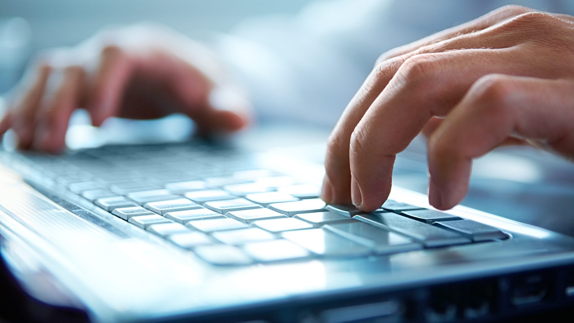 Hands typing at laptop